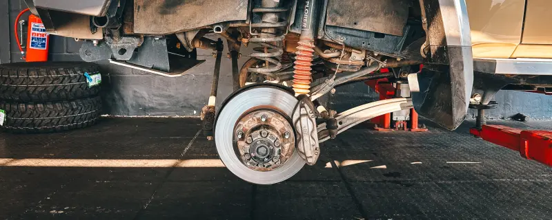 Front suspension and brake disc on a 4x4 up on a workshop lift